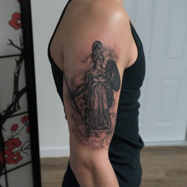 realism black and grey Athena statue with clouds tattoo on outer shoulder area - endless heights tattoo by artist dj donald voelker