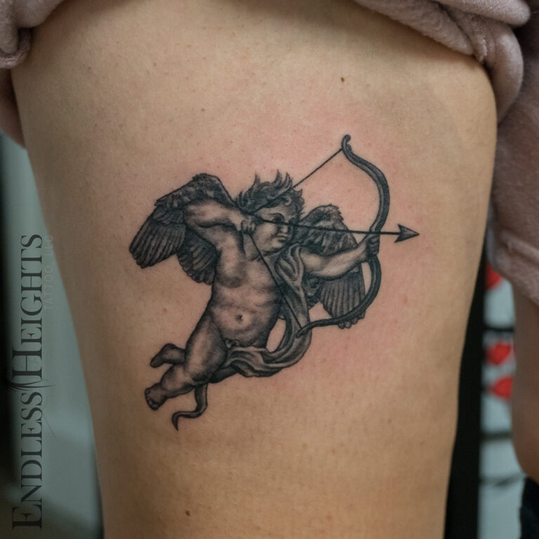 black and grey realism cupid on thigh - endless heights tattoo by artist dj donald voelker